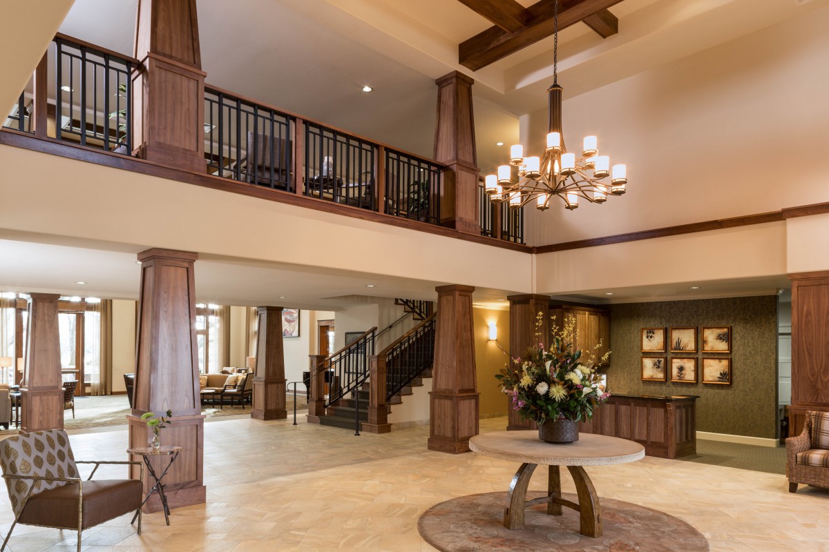 A spacious lobby area with a grand chandelier, wooden beams, and elegant decor.