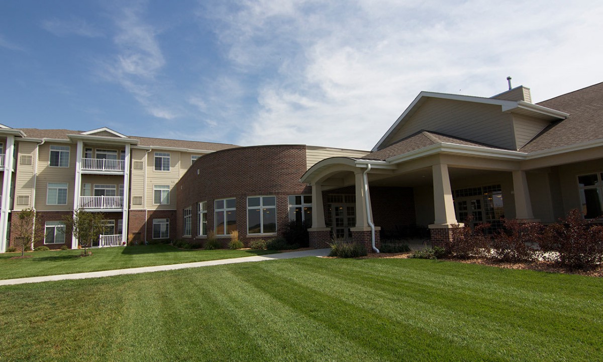 A modern building with a well-maintained lawn and clear skies.