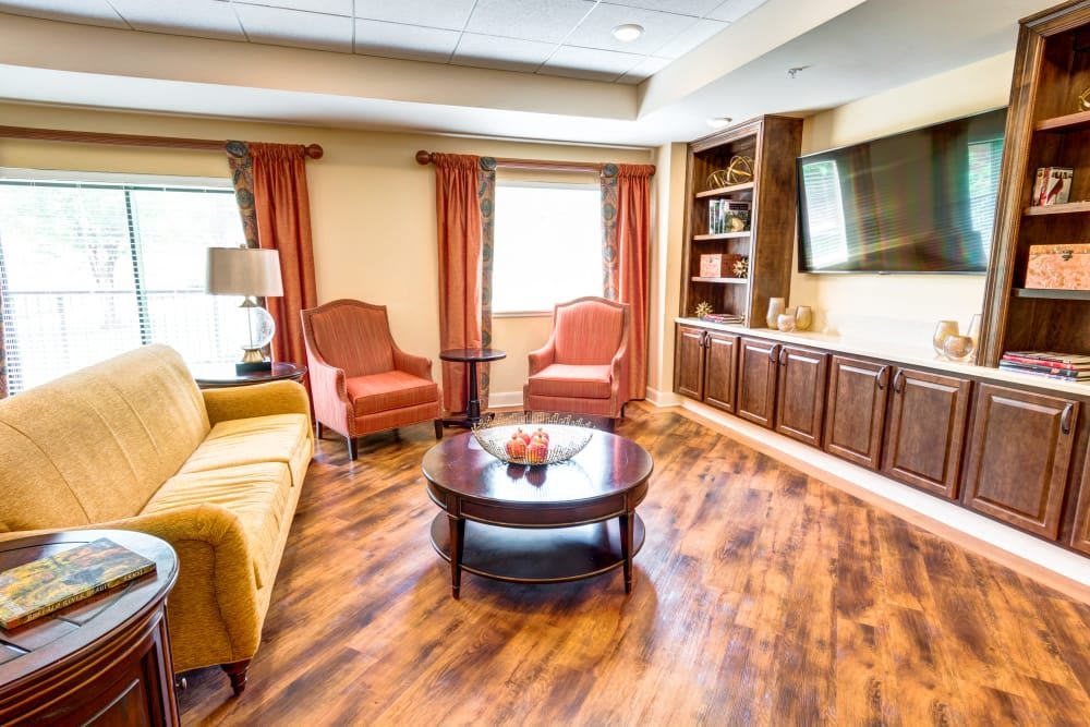 A cozy living room with a sofa, armchairs, and a TV mounted above built-in shelving.