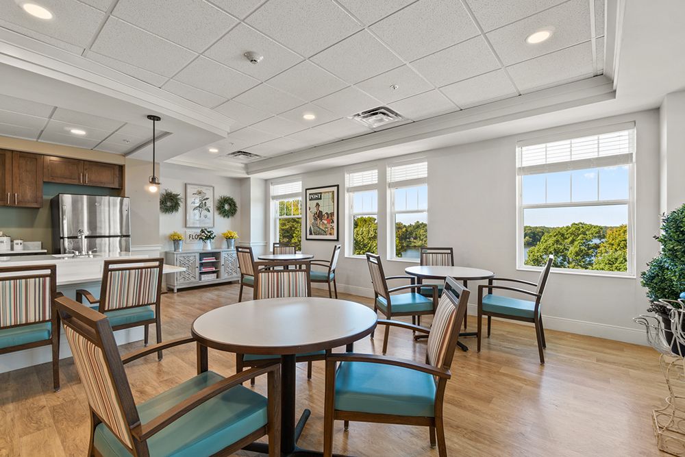 A modern dining area with round tables and chairs, featuring large windows that allow natural light to fill the space.