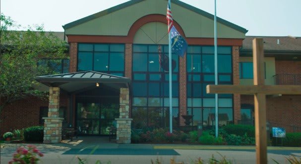 A modern building with large glass windows and flags at the entrance.