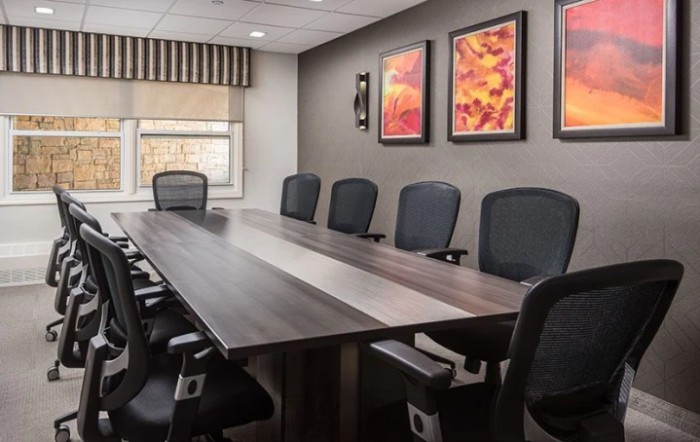 A modern conference room with a sleek meeting table and ergonomic chairs, adorned with vibrant artwork on the walls.