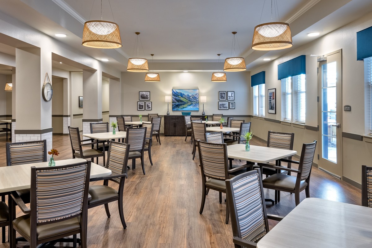 A modern dining area with neatly arranged tables and chairs, warm lighting, and stylish decor.
