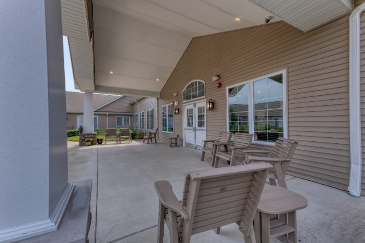 A spacious patio area with chairs and tables, covered by a large roof, next to a building with large windows.