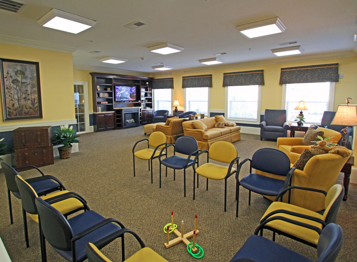 A well-lit waiting room with multiple chairs arranged in a circle and a casual seating area.