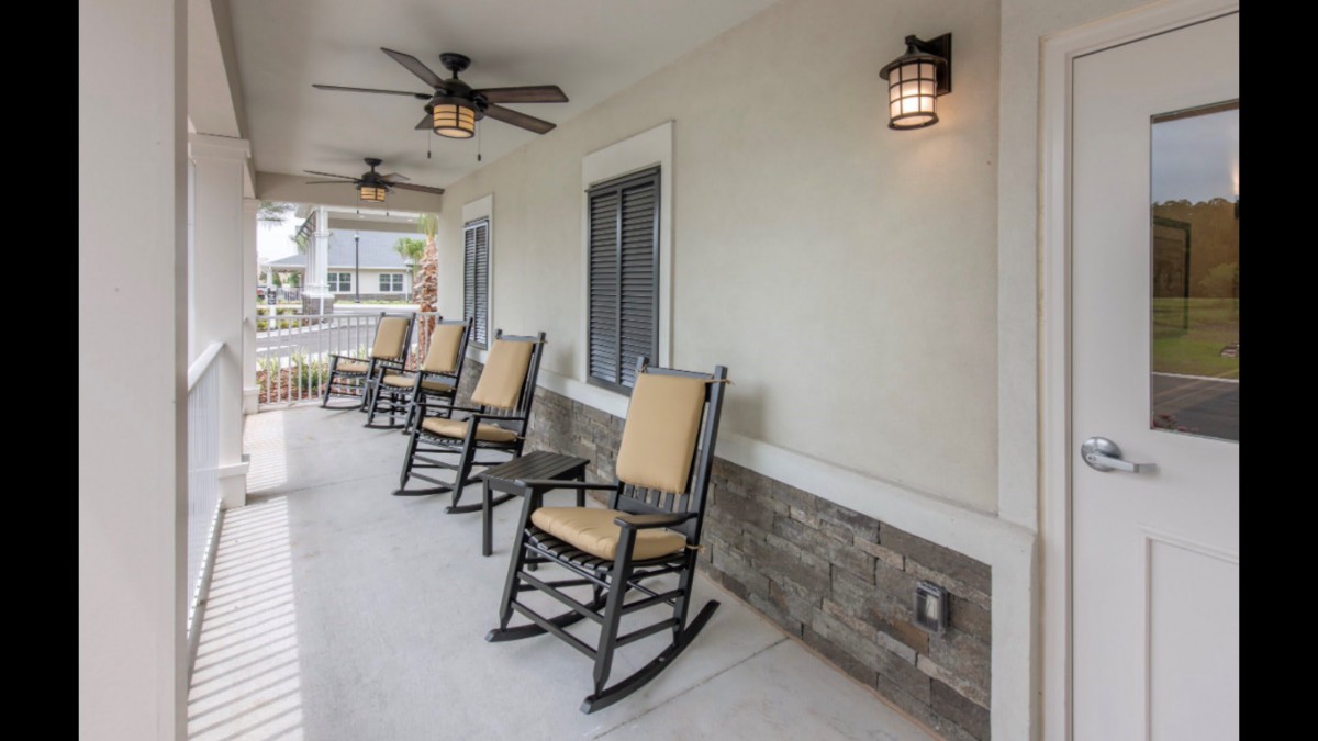 A cozy porch featuring rocking chairs, ceiling fans, and lantern-style lighting.