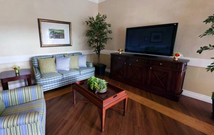 A cozy living room with a striped sofa, wooden coffee table, and a large television.