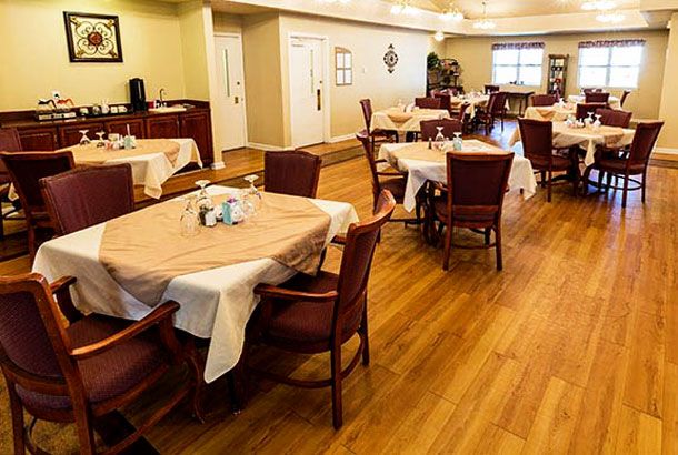 A cozy dining room with neatly arranged tables and chairs on a wooden floor.