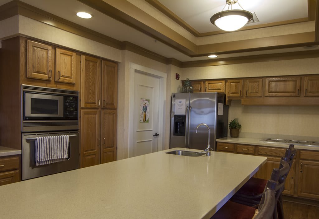 A modern kitchen with wooden cabinets, stainless steel appliances, and a large central island.