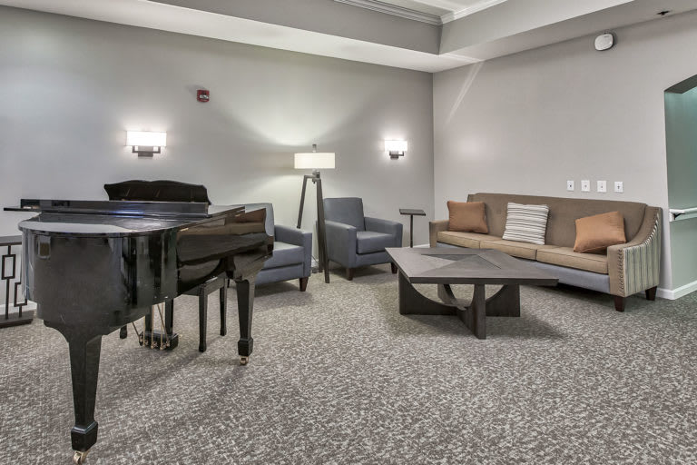 A modern living room with a grand piano, sofa, chairs, and a coffee table.