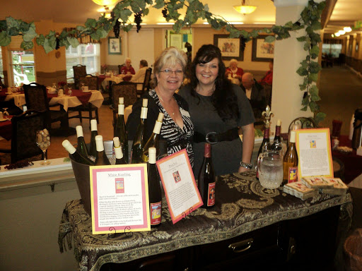 Two women showcasing a variety of wines at an event in a restaurant setting.