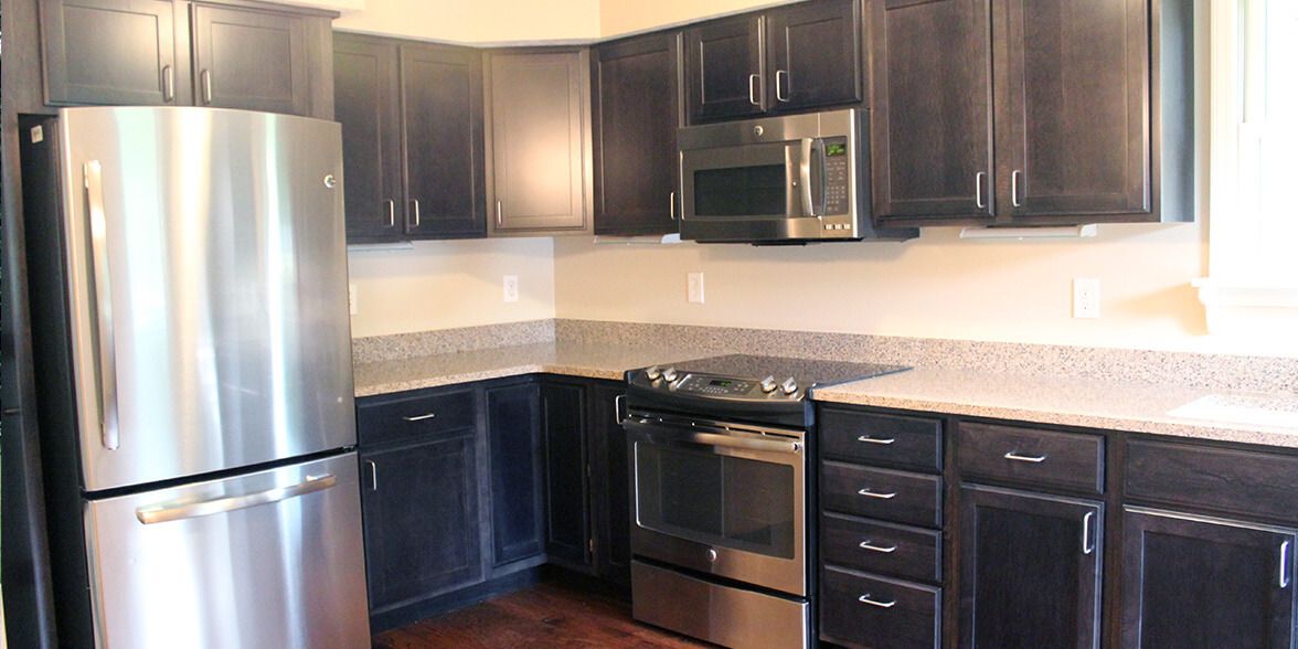 A modern kitchen with dark cabinets and stainless steel appliances.