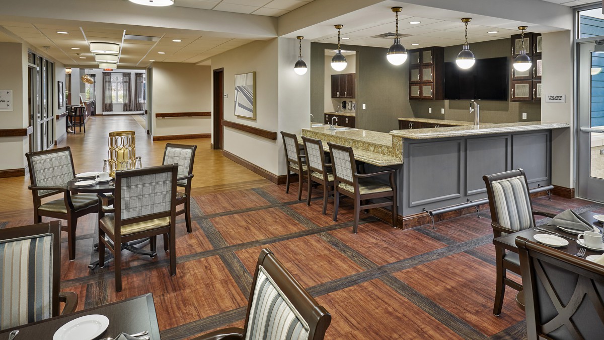 A modern lounge area with a bar, featuring wooden floors, comfortable seating, and elegant lighting.