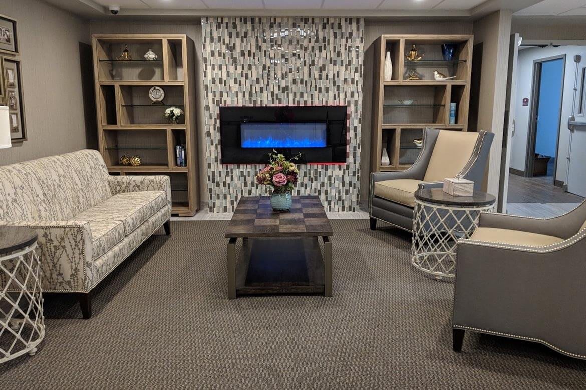 A cozy living room with a modern fireplace, stylish furniture, and decorative bookshelves.