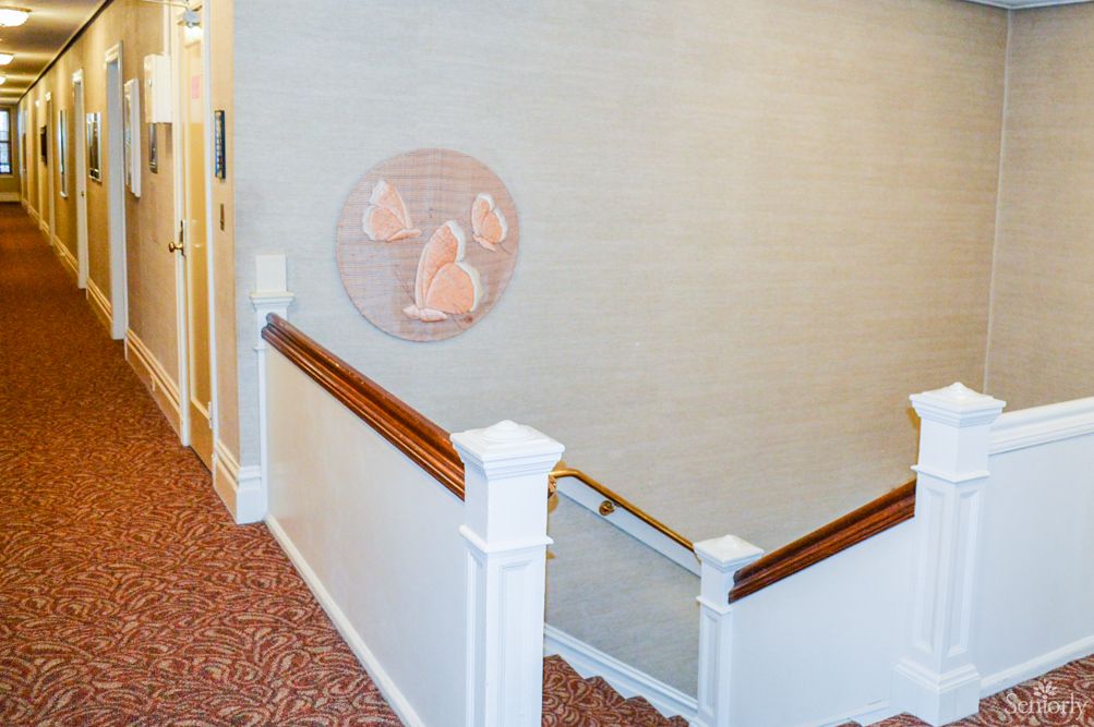 A carpeted staircase with a wooden handrail and decorative wall art.