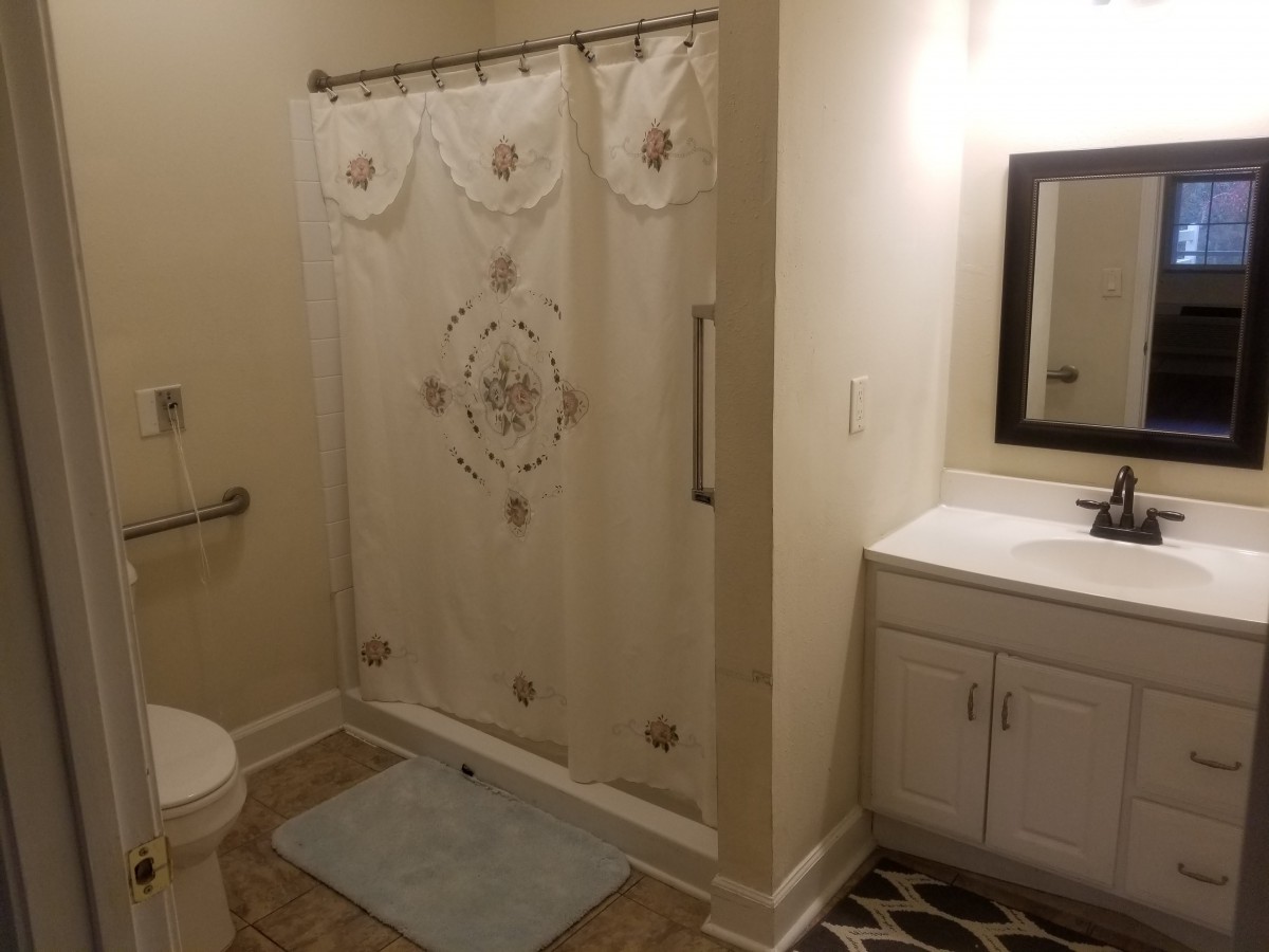 A clean and well-lit bathroom with a shower, sink, and toilet.