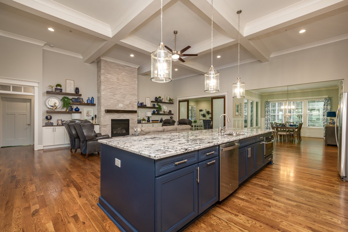 A modern kitchen with a large island and pendant lighting, featuring a spacious open floor plan.