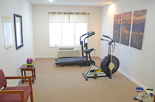 A well-equipped home gym featuring a treadmill, elliptical machine, and air bike, perfect for exercising in comfort.
