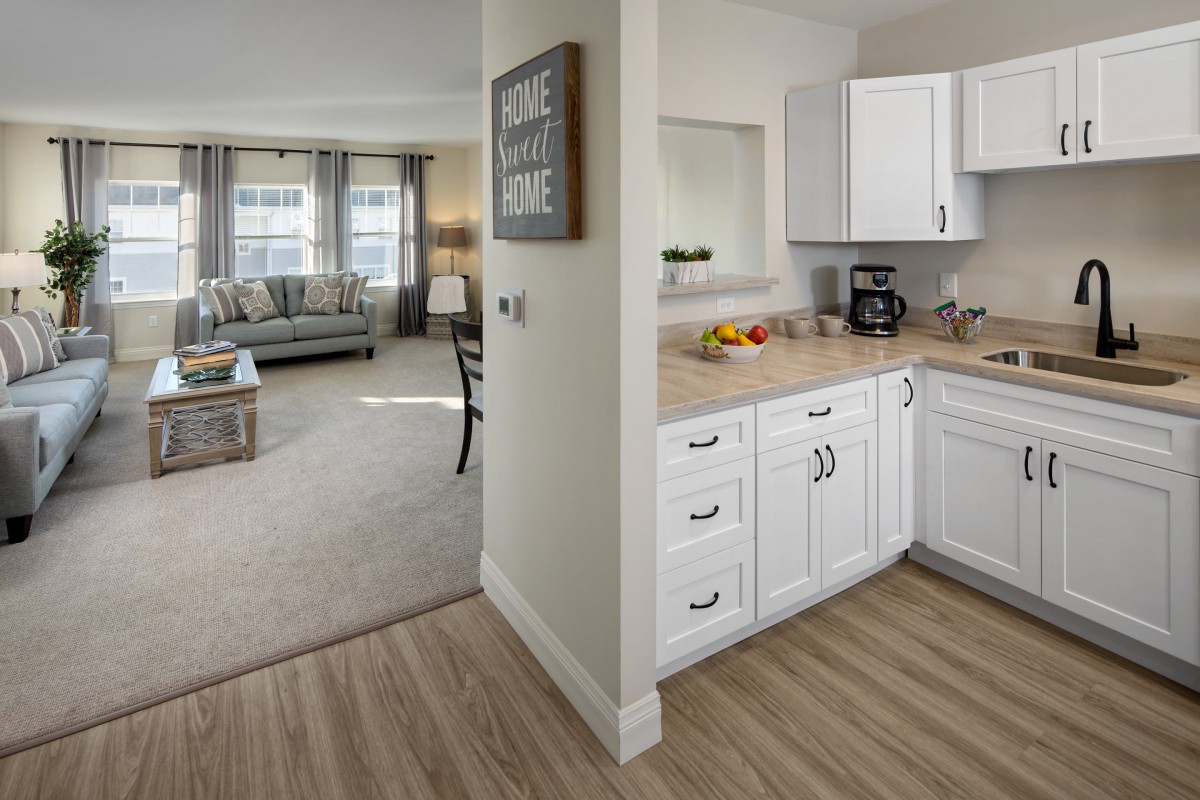 A modern apartment interior featuring an open floor plan with a kitchen and living room.
