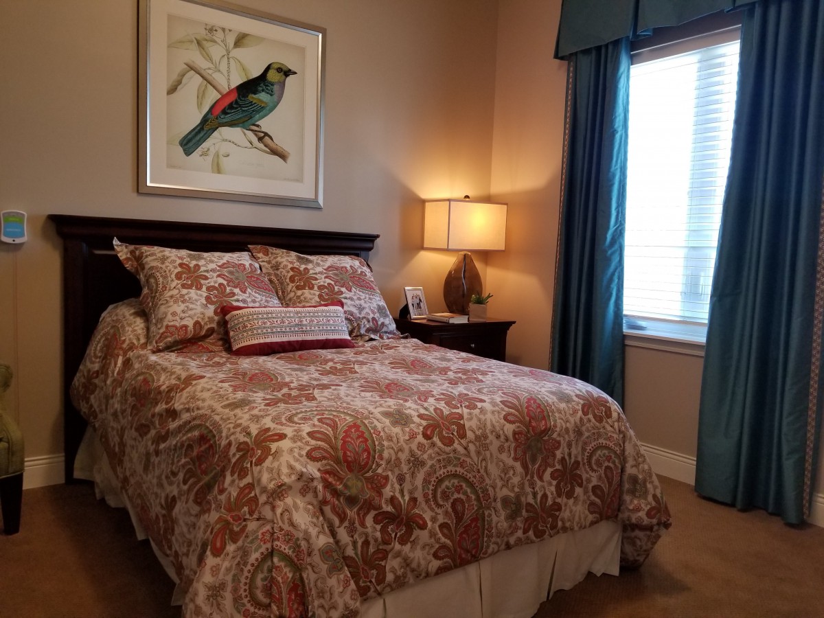 Cozy bedroom with patterned bedding, a bedside lamp, and wall art.