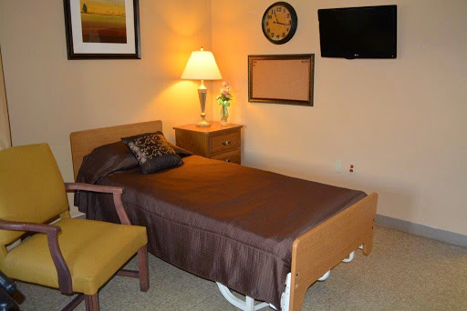 A cozy bedroom featuring a single bed, a bedside lamp, and a wall-mounted television.