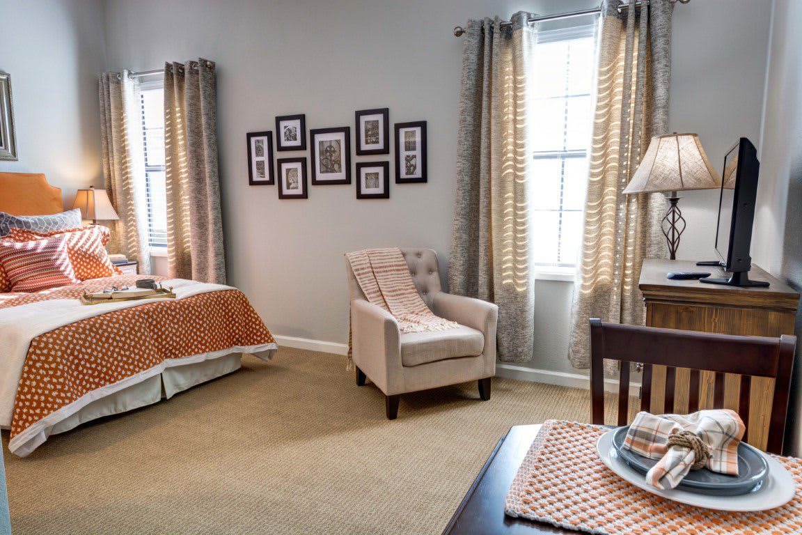 A cozy bedroom with a comfortable armchair, neatly made bed, and decorative elements.