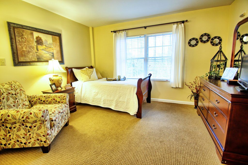 A cozy bedroom featuring a single bed, traditional decor, and a window with curtains.