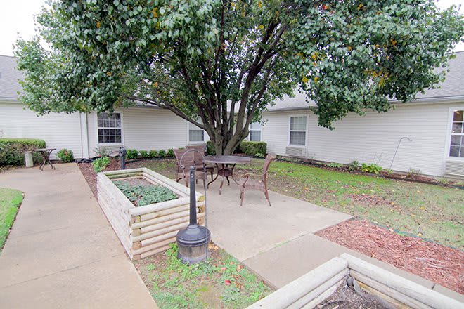 A cozy outdoor patio area with seating surrounded by lush greenery.
