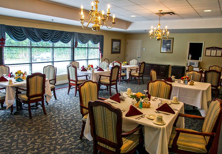 An elegant dining room with set tables and chandeliers.