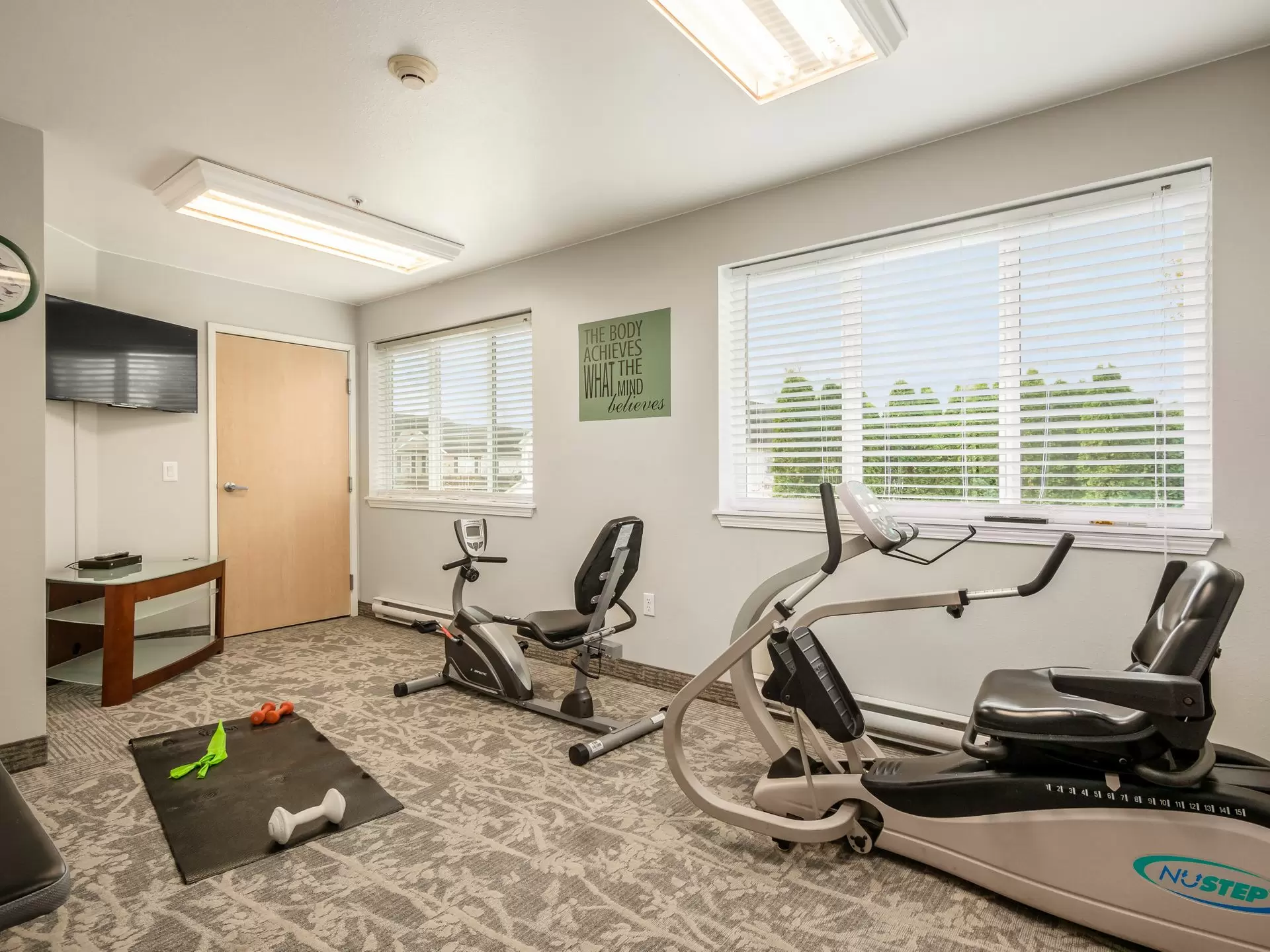 A small indoor exercise room with gym equipment, including a stationary bike and an elliptical machine.