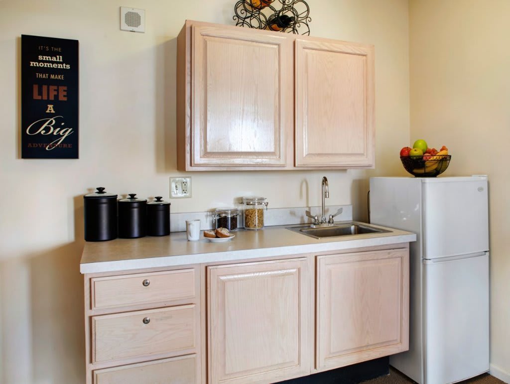 A small kitchen space with light wood cabinets and a compact refrigerator.