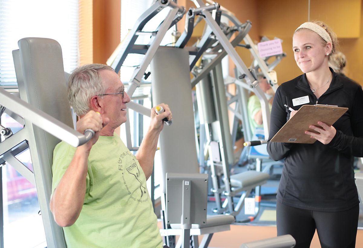 A personal trainer guiding a client during a workout session at the gym.
