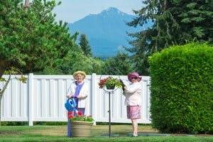 Two people tending to a garden with mountains in the background.