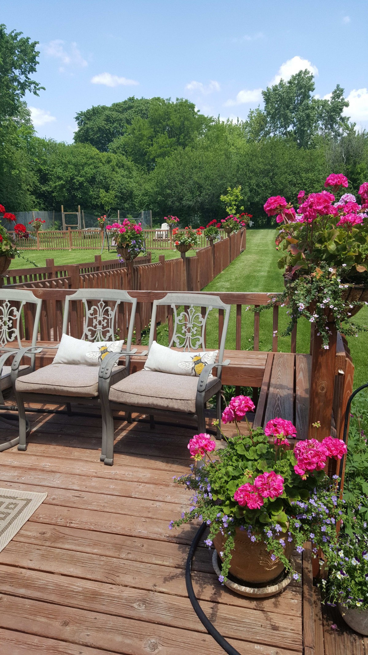 A beautifully landscaped garden with cozy outdoor seating and vibrant flowers on a wooden deck.