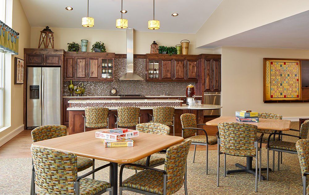 A modern kitchen and dining area with wooden cabinets, bar stools, and overhead lighting.