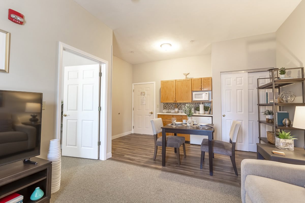 A view of a cozy apartment featuring an open kitchen and dining area with wooden furniture.