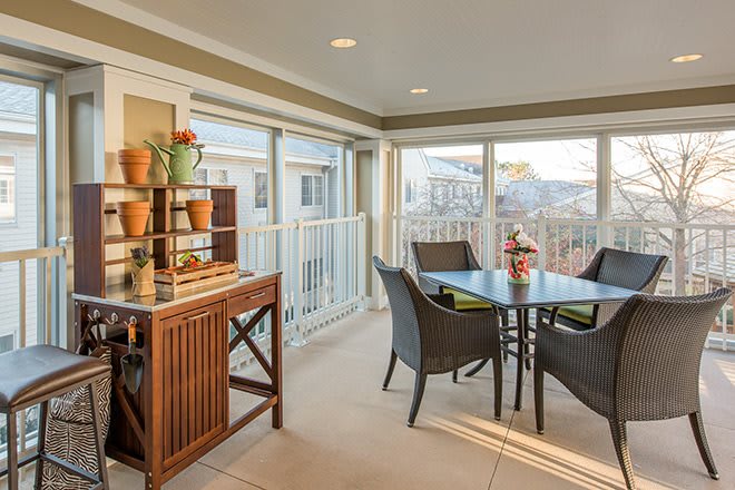 A cozy sunroom with rattan furniture and decorative pots, bathed in natural light.