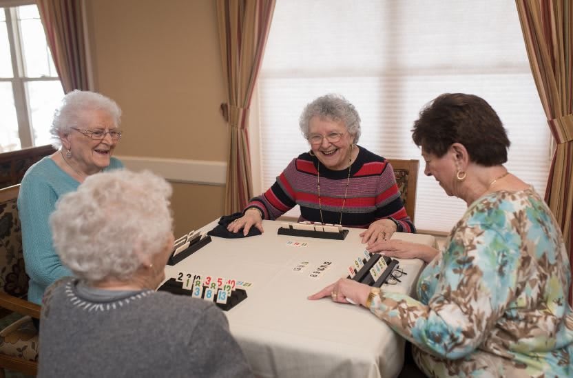 A group of elderly women enjoying a game together at a table indoors.