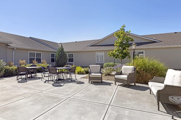 A sunny courtyard featuring outdoor seating and landscaping.