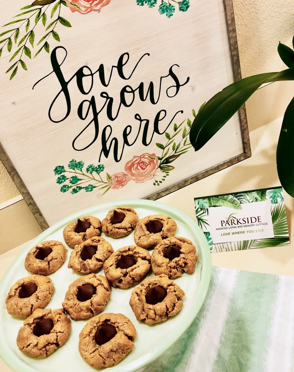 A delightful plate of homemade cookies sits beside a charming sign that reads 'Love grows here'.