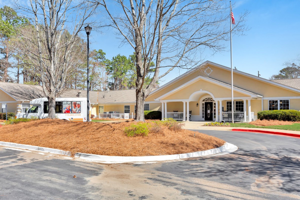 A residential facility with a landscaped entrance featuring trees and a flag.