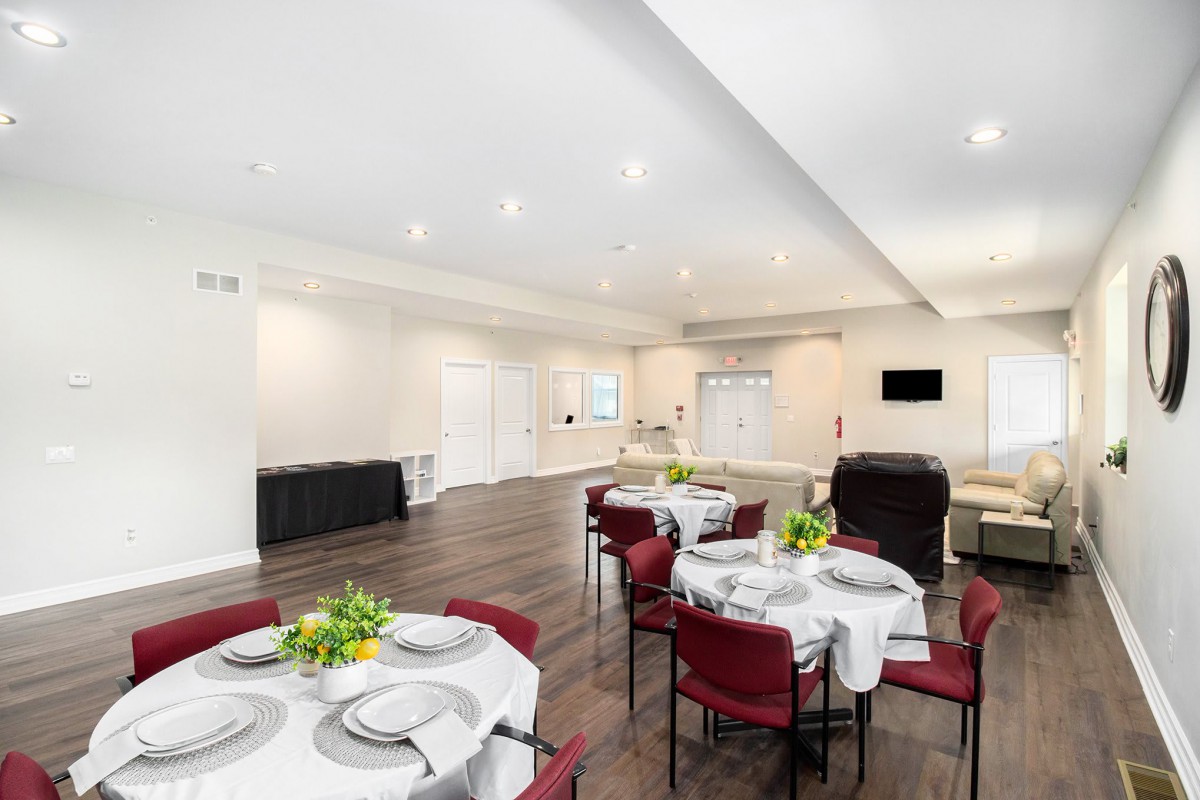 A modern dining room setup with tables and chairs, decorated with flowers, ideal for events.