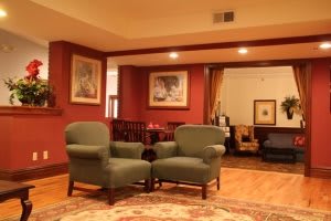 A cozy living room with green armchairs and wall art under warm lighting.
