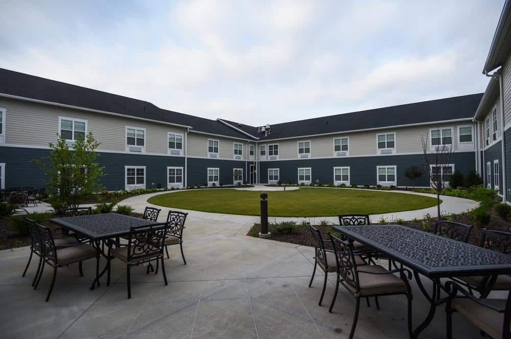 A modern building with a spacious courtyard featuring outdoor seating and a well-maintained lawn.