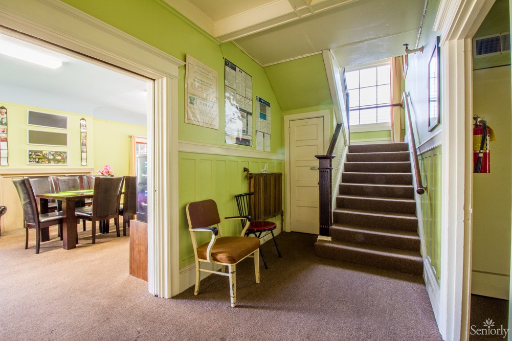 A traditional hallway with green walls featuring a staircase and adjoining dining room.