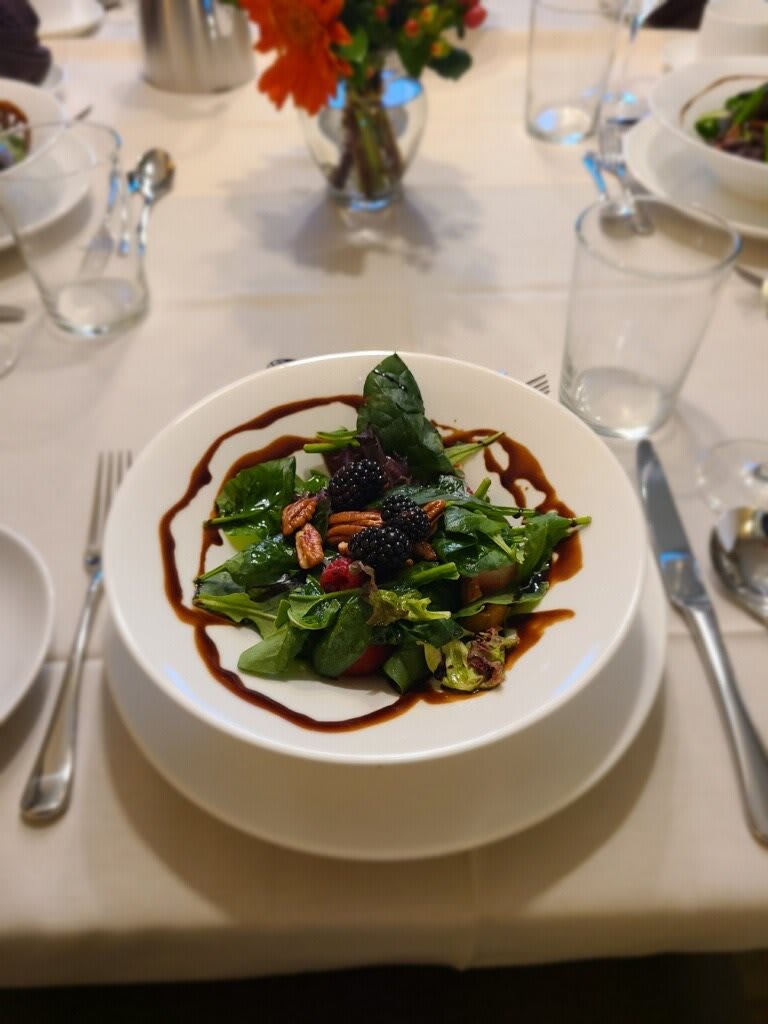 A gourmet salad with fresh greens, nuts, and berries elegantly plated with a balsamic glaze.