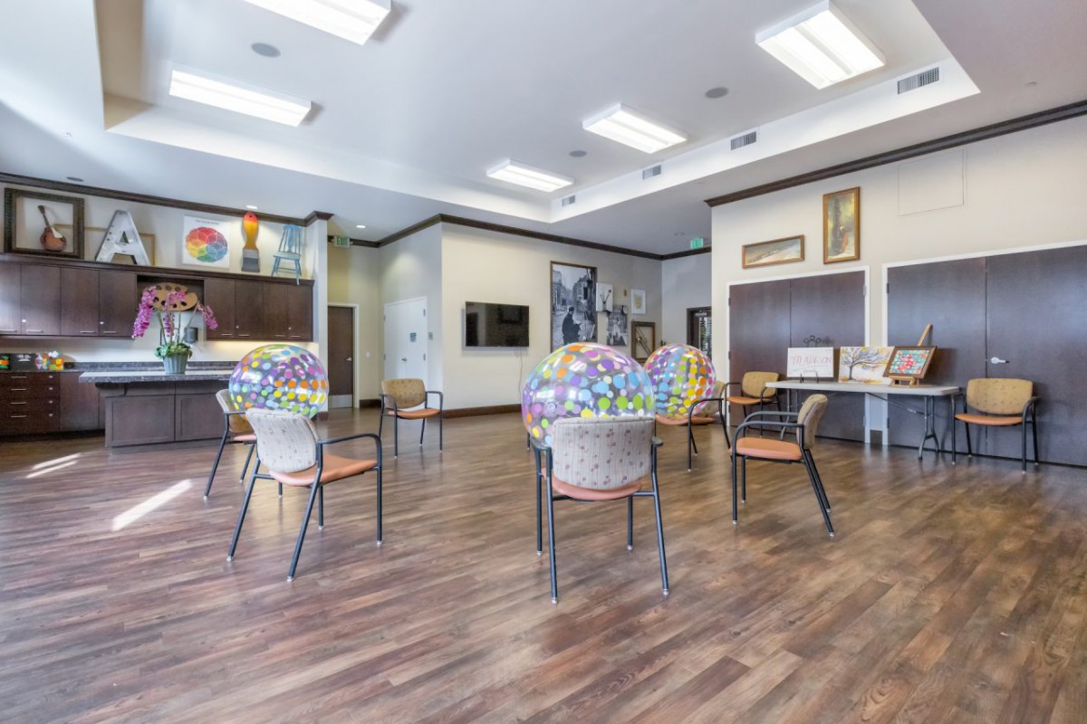 A modern waiting area with chairs and tables arranged on wooden flooring.