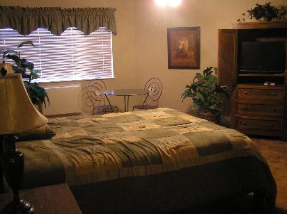 Cozy bedroom with a large bed, small table and chairs near the window.