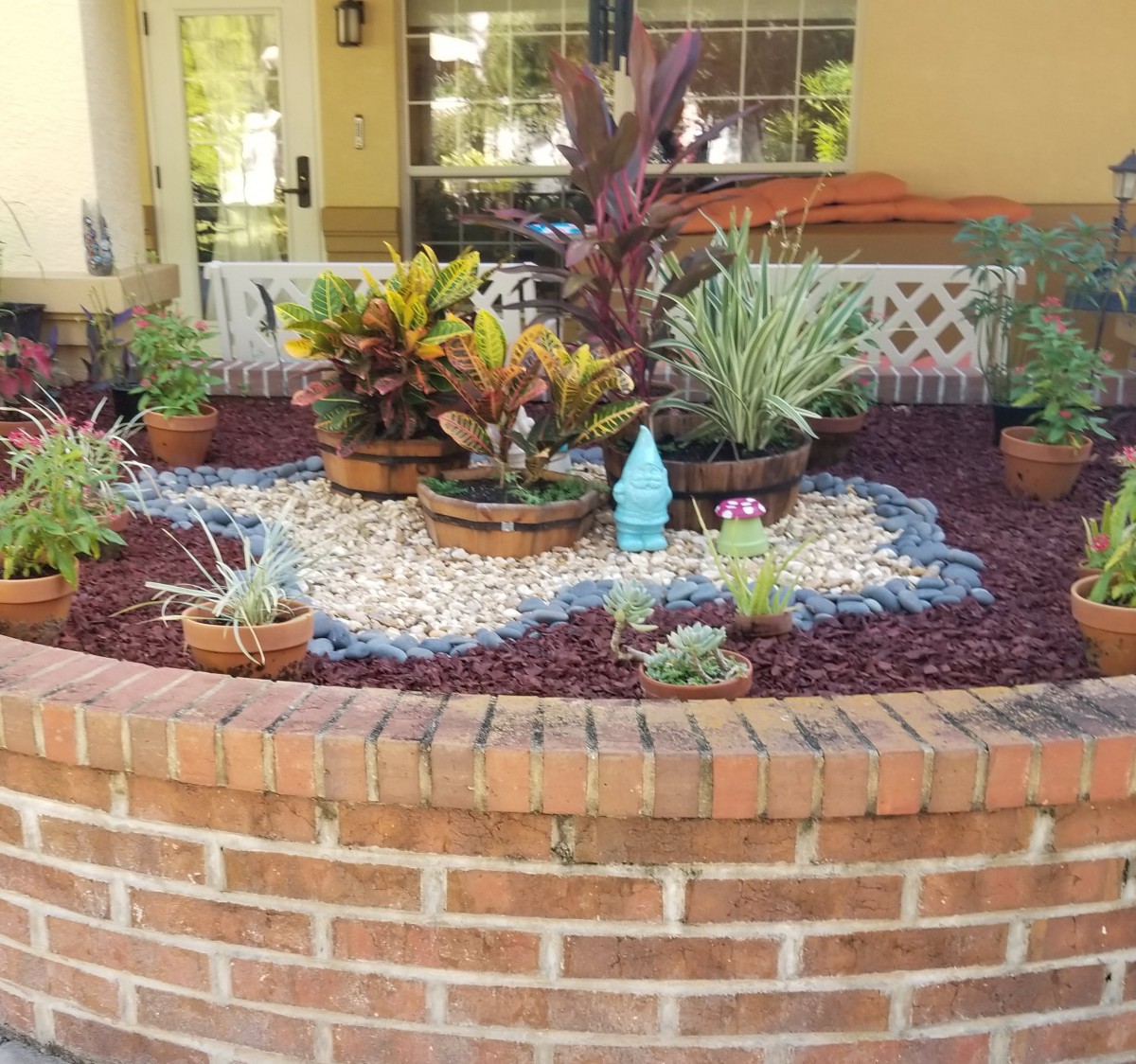 A beautifully arranged garden with a variety of succulents and decorative stones in a brick planter.