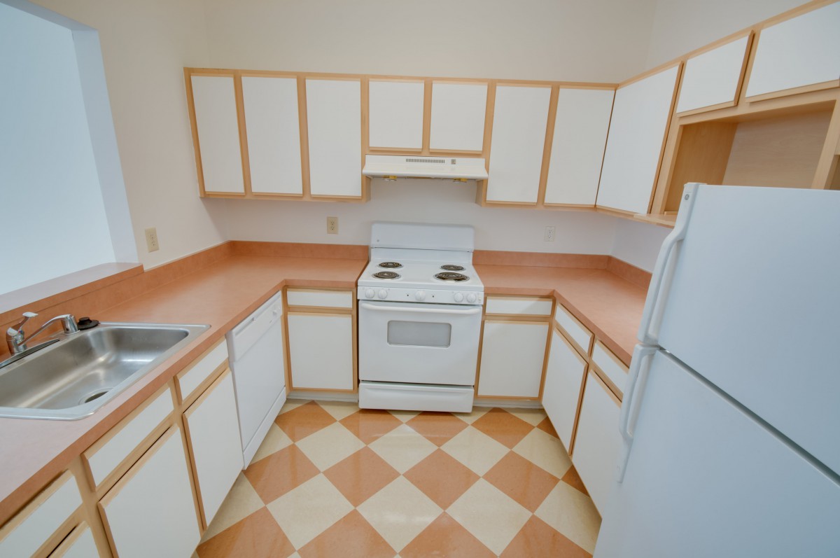 A small kitchen with white cabinets, a stove, and a refrigerator.